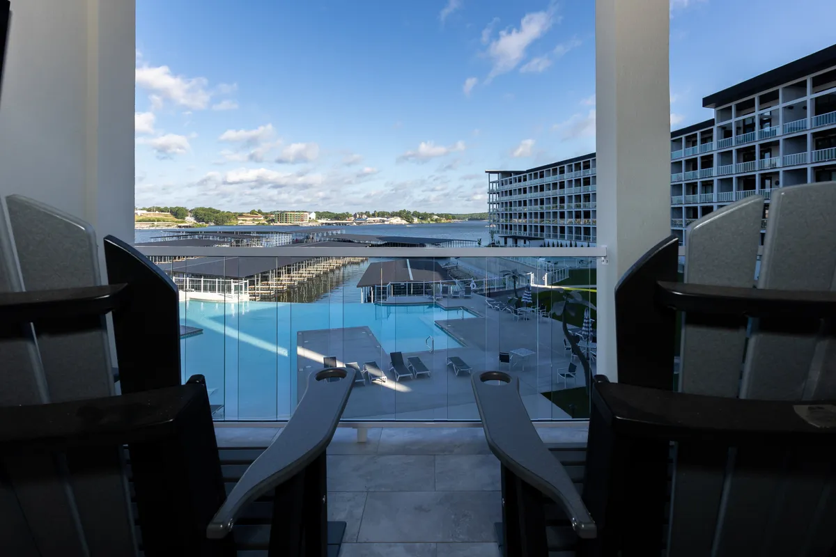 An exterior view features a sparkling swimming pool set against a waterfront backdrop and modern architecture. Lounge chairs and gathering spots surround the pool, inviting guests to socialize or unwind outdoors while enjoying scenic views and resort-style amenities.