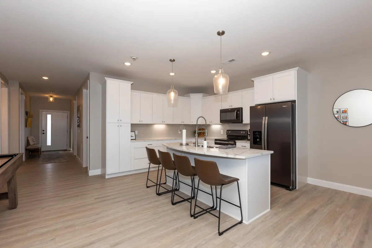 A modern kitchen featuring a spacious island with bar stools, sleek appliances, and pendant lights overhead. The setup is open and designed for both cooking and entertaining, inviting both casual breakfasts and festive gatherings.