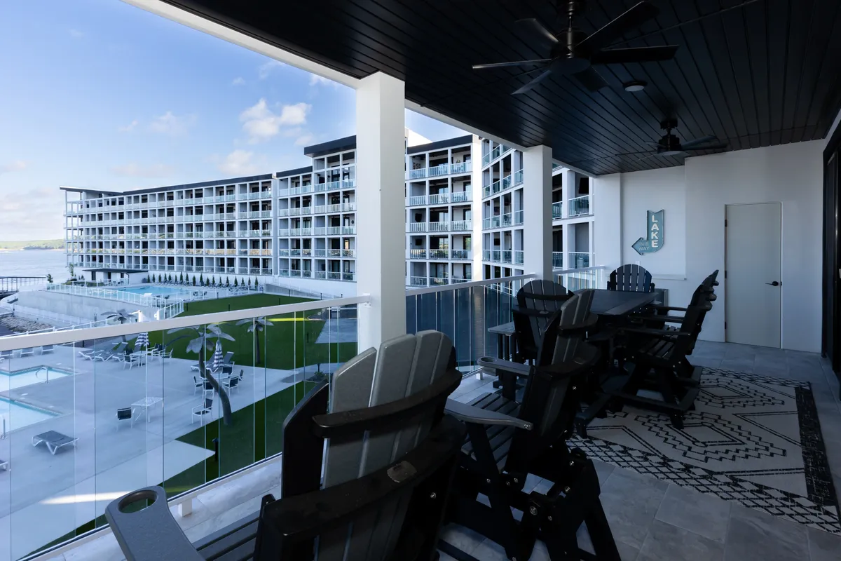 A serene outdoor setting with comfortable balcony seating overlooking a sparkling swimming pool and expansive landscape. The view captures inviting outdoor spaces for relaxation and quiet moments after a day of adventure.